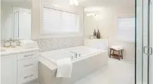  ??  ?? The ensuite boasts two vanities and a deep soaker tub.