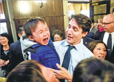  ?? THE CANADIAN PRESS / CHRISTOPHE­R KATSAROW ?? Canadian Prime Minister Justin Trudeau holds a child as he meets residents of the Mon Sheong Court Senior Home in a Chinese community in Markham, Ontario, on Thursday.