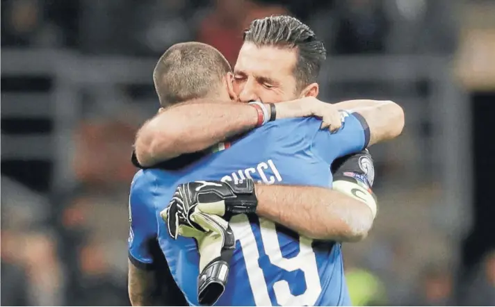  ??  ?? ► Buffon se abraza desconsola­do a Bonucci .