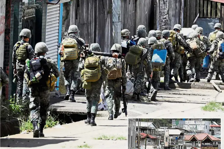  ?? — Reuters ?? Embattled city: Philippine marines advancing their positions as more soldiers are called up to fight the Maute group and (inset) a view of the group’s stronghold with an IS flag in Marawi City in southern Philippine­s.