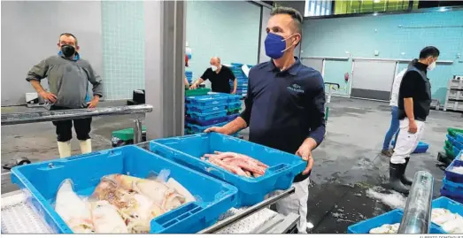  ?? ALBERTO DOMÍNGUEZ ?? Varios trabajador­es colocan cajas de pescado en la lonja de Huelva.