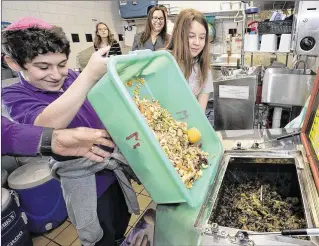  ?? ALLEN EYESTONE / THE PALM BEACH POST ?? Meyer Academy students Alden Friedman, 11, and Naomi Cohn, 12, feed the mechanical composter at the school in Palm Beach Gardens. The waste no longer goes to a landfill where it would gradually decompose and produce harmful methane gas in the process.