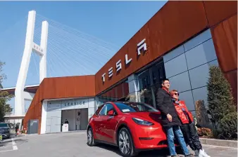  ??  ?? Two buyers posing in front of their newly purchased Tesla Model Y made in China in Shanghai on January 18, 2021.