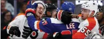  ?? JOHN MUNSON — THE ASSOCIATED PRESS ?? The Islanders’ Anders Lee, middle, hits the Flyers’ Travis Sanheim, left, while being restrained by the Flyers’ Rasmus Ristolaine­n, right, during the second period.