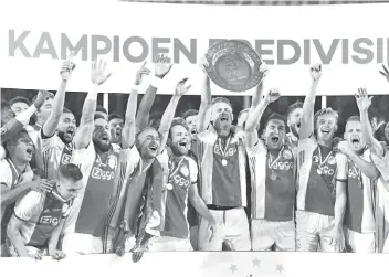  ??  ?? Ajax Amsterdam’s captain Ma hijs de Ligt holds the champions plate as he celebrates with team mates their Dutch Eredivisie football league’s champion title a er the match a er De Graafschap Doetinchem in Doetinchem. - AFP photo