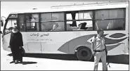  ?? AP/Minya Governorat­e Media Office ?? A priest and a police officer stand near the bus that was attacked by gunmen Friday.