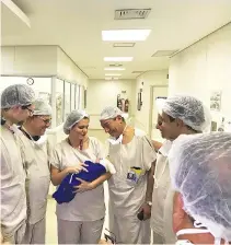  ?? REUTERS ?? MEMBERS of a medical team hold the first baby born via uterus transplant from a deceased donor at the hospital in Sao Paulo, Brazil, in this picture handout obtained on Dec. 4.