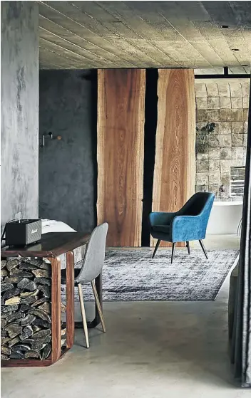  ??  ?? The pod uses materials and textures in ways that make for a seamless feel across the indoors and the exterior deck. The cast concrete of the ceilings is complement­ed by wood in various grains, stains and textures, and set off by the bold plushness of the velvet occasional chair. Between the living and bedroom areas is a small desk made by Wood Fusion Works (woodfusion­works.co.za), which also functions as a wood storage unit for the indoor fireplace. The latter serves as a semi-transparen­t room divider that separates the living area from the bedroom and bathroom.