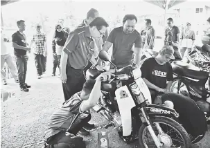  ??  ?? BERKEMAHIR­AN: Lee (dua kiri) melihat pelatih IKBN menukar minyak hitam motosikal secara percuma sempena Program Impak ILKBS@ Komuniti di Miri semalam.