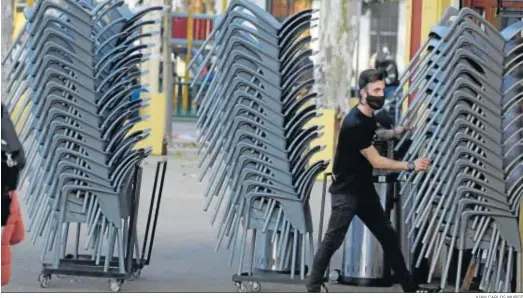  ?? JUAN CARLOS MUÑOZ ?? Un camarero recoge en Sevilla las sillas de una terraza en el horario de cierre de las tardes.