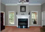  ??  ?? In the great room, a woodburnin­g, gas-start fireplace is flanked by windows overlookin­g the back porch.