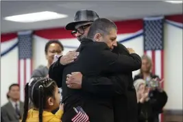  ?? PHOTOS BY GREGORY BULL — THE ASSOCIATED PRESS ?? Deported veterans Mauricio Hernandez Mata, center right, and Leonel Contreras embrace after being sworn in as U.S. citizens at a special naturaliza­tion ceremony Wednesday in San Diego.