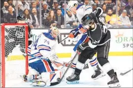  ?? WALLY SKALIJ Los Angeles Times ?? PHILIP DANAULT, right, tries to poke a shot past Edmonton goalie Stuart Skinner as Vincent Desharnais defends. The Kings are 0 for 10 on the power play.