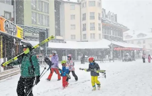  ?? // ABC ?? Varios esquiadore­s cruzan ayer la plaza principal de Pradollano, en Sierra Nevada, bajo la nieve