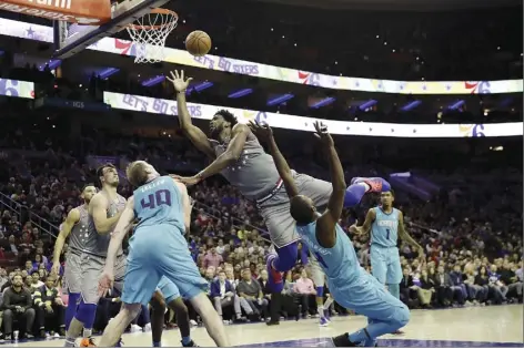  ?? AP photo ?? Philadelph­ia’s Joel Embiid tries to get a shot past Charlotte’s Michael Kidd-Gilchrist and Cody Zeller during the second half of the 76ers’ 133-132 overtime win over the Hornets on Friday.