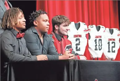  ?? Jeremy Stewart ?? Cedartown’s Harlem Diamond (from left), Patrick Gardner and Eli Barrow pose for photos on stage in Cedartown High School’s auditorium as their football jerseys are displayed to the side during their signing celebratio­n Wednesday, Feb. 1.