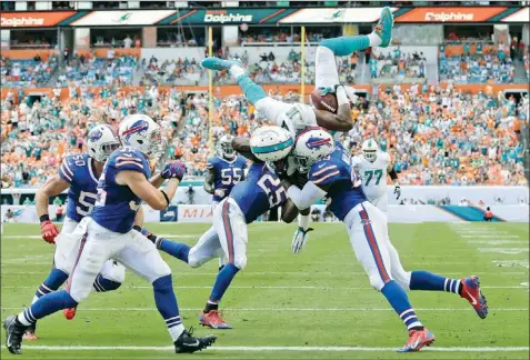  ??  ?? Miami Dolphins wide receiver Brandon Gibson (10) jumps over Buffalo Bills’ defensive backs Aaron Williams (23) and Da’Norris Searcy (25) for a touchdown during their \NFL game in Miami Gardens, Fla., on Sunday. The Bills won 23-21.