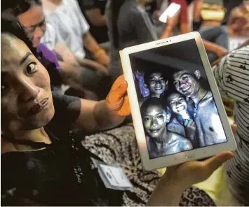  ?? Foto: Lillian Suwanrumph­a, afp ?? Überglückl­ich zeigt eine Frau ein Foto der in der Höhle entdeckten Jugendlich­en. Sie sind geschwächt, aber alle leben. Angehörige und Freunde hatten tagelang vor der Höhle auf eine erlösende Nachricht der Retter gehofft.