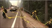  ?? SARA NEVIS — THE SACRAMENTO BEE VIA AP ?? Fire crews carry a hose down a hill as the Caldor Fire burns on both sides of Highway 50about 10miles east of Kyburz on Aug. 26as the fire pushes east prompting evacuation orders all the way to Echo Summit.