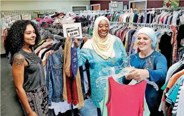  ?? [PHOTO BY JIM BECKEL, THE OKLAHOMAN] ?? Courtney Boneta, a junior intake coordinato­r and thrift store worker; Deborah Boneta, executive director of the Surayya Anne Foundation-OKC; and Becky Atiyeh, the organizati­on’s president talk in the women’s clothing area of the new Surayya Anne thrift store.