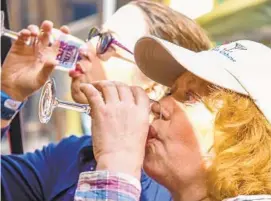  ?? PHIL GROUT/FOR THE BALTIMORE SUN MEDIA GROUP ?? Casey Brown, foreground, of Westminste­r and her friend Diana DeMarco of Chambersbu­rg, Pa., find a wine that’s to their liking as they sample wine along Main Street, Westminste­r, for Sunday’s annual Wine Stroll. The event also included live music,...