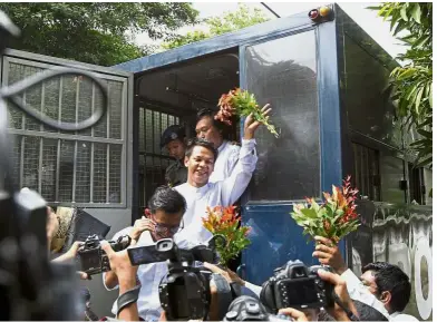  ?? — AP ?? Staying positive: The journalist­s from Eleven Media Group waving as they exit a police truck for their trial in Yangon.