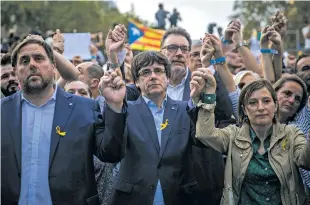  ?? SANTI PALACIOS/THE ASSOCIATED PRESS ?? Catalan President Carles Puigdemont, center, Deputy President Oriol Junqueras, left, and Carme Forcadell, speaker of the house in the Catalan Parliament, hold hands Saturday during a protest in Barcelona against the National Court’s decision to...