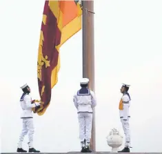  ??  ?? Sri Lankan Navy officers lower the national flag at the flag square in Colombo, Sri Lanka. — Reuters photo