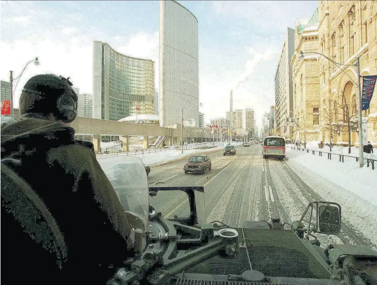  ?? PHOTOS BY THOMAS CHENG / AFP / GETTY IMAGES ?? Canadian Army officer John Dunn patrols downtown Toronto in an armoured personnel carrier on Jan. 15, 1999, after the city was inundated with snow, and later, scorn.