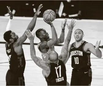  ?? Ashley Landis / Associated Press ?? Oklahoma City’s Dennis Schroder, center, shoots as the Rockets’ Eric Gordon (10), P.J. Tucker (17) and Jeff Green defend during the first half on Saturday in Lake Buena Vista, Fla.