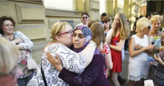  ??  ?? A Muslim woman hugs another lady in central Manchester, northwest England on Friday, as a gesture of solidarity. (AFP)