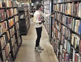  ?? Dania Maxwell Los Angeles Times ?? TIM PRONOVOST searches for books to deliver to customers at the Last Bookstore in downtown L.A., one of the stores that has reopened for curbside pickup.