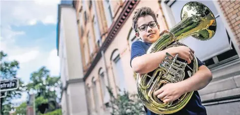  ?? RP-FOTO: ANDREAS BRETZ ?? Kaleb Heckenthal­er (11) würde gerne an der städtische­n Musikschul­e (im Hintergrun­d) weiterlern­en. Einen Platz hat er bislang nicht.