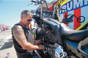  ?? STEPHEN GROVES/ASSOCIATED PRESS ?? Chris Cox, founder of Bikers for Trump, examines his motorcycle Aug. 8 outside the Bikers for Trump trailer he brought to the Sturgis Motorcyle Rally in South Dakota.