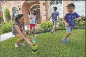  ??  ?? Vicky Li Yip (left) sets up a bubble machine for her children (from left) Kelsey, Toby and Jesse, outside their home July 10 in Houston.