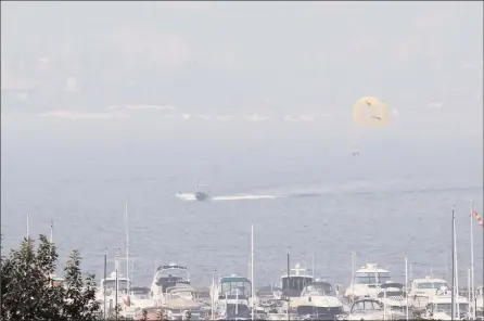  ?? RON SEYMOUR/ The Daily Courier ?? A parasailer being towed behind a boat on Okanagan Lake might have had trouble discerning landmarks below given the smoky skies that enveloped Kelowna early Tuesday morning.