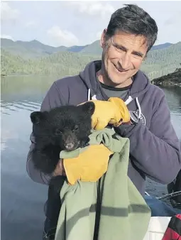  ??  ?? John Forde, co-owner of the Whale Centre in Tofino, holds an orphaned black bear cub near Tofino.