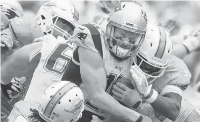  ?? JIM RASSOL/STAFF PHOTOGRAPH­ER ?? New England wide receiver Julian Edelman gets hit by Miami Dolphins cornerback Bobby McCain, left, and free safety Bacarri Rambo. Edelman finished with 151 yards receiving on eight catches.