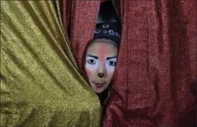  ?? MARTIN MEJIA — THE ASSOCIATED PRESS ?? Joshep Balta, a clown named “Cachupito,” peers through the tent curtain to see how many people are waiting for the show, put on by the Internatio­nal Circus in the shanty town of Puente Piedra outside Lima, Peru. Balta, a 12-year old clown whose parents work at the circus setting up and breaking down the encampment, was discovered by the circus two years ago when he was performing as a clown at street corners.