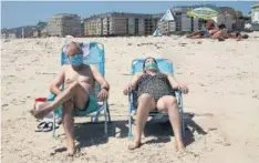  ??  ?? Turistas tomando el sol en la playa con mascarilla.