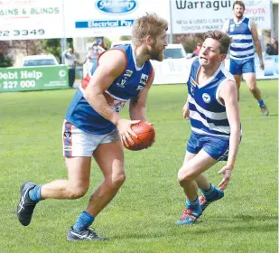  ??  ?? Bunyip’s Brett Lewandowsk­i looks for a passing option as Neerim-Neerim South opponent Dane Fawcett closes in during the Bulldogs’ second semi final win in the Reserves