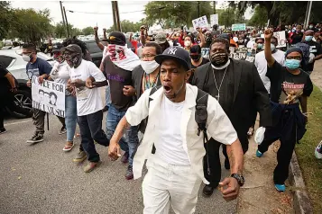  ?? Associated Press ?? ■ Malik Muhammad, center, joins a group of people marching from the Glynn County Courthouse in downtown to a police station after a rally May 16 to protest the shooting of Ahmaud Arbery in Brunswick, Ga.