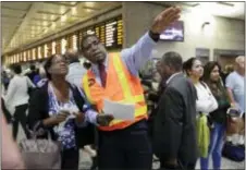  ?? RICHARD DREW — THE ASSOCIATED PRESS ?? Long Island Rail Road usher Jeff Carter aides a passenger in New York’s Penn Station, Monday. Amtrak has begun extensive repairs Monday to tracks and signals in Penn Station, which it owns and operates. Monday morning’s rush got off to a slow start...