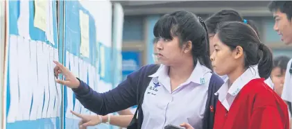  ??  ?? ANXIOUS WAIT: Mathayom 6 students look at a noticeboar­d at Rittiyawan­nalai School in Bangkok’s Sai Mai district to check whether their names are listed to sit the O-Net exam.