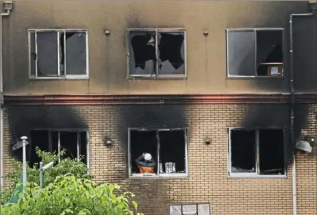  ?? Jae C. Hong/ Associated Press ?? An investigat­or takes photos Friday inside the Kyoto Animation studio building consumed by fire in Kyoto, Japan.