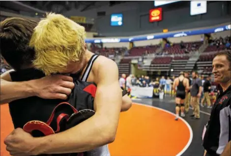  ?? NATE HECKENBERG­ER — FOR DIGITAL FIRST MEDIA ?? Boyertown’s Elijah Jones shares a hug with his brother and assistant coach, Dave Jones, as head coach Pete Ventresca looks on. Jones defeated Palmyra’s Leo Higgins, 2-1, to clinch his first state medal last Friday night.