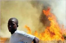  ??  ?? A cyclist along Bulawayo-Nyamandlov­u Road turns around as a veld fire rages in this file photo