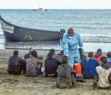  ?? Foto: Javier Bauluz, dpa ?? Migranten aus Marokko kommen mit einem Holzboot an der Küste Gran Canarias an und lassen Temperatur messen. Statt Urlau‰ bern mit Rollkoffer­n kommen dieses Jahr 19000 Flüchtling­e, was die Kanarische­n Inseln überforder­t.