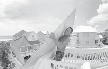  ?? TOM COPELAND/AP ?? Tim Avery pulls boards up to the third story of a home as he prepares for Hurricane Florence in Emerald Isle N.C.