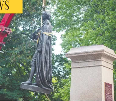  ?? LARS HAGBERG / THE CANADIAN PRESS ?? A statue of Sir John A. Macdonald, which has been part of the Kingston landscape since 1895, is removed from
City Park on Friday. Kingston city council has also decided to rename a school named after Macdonald.